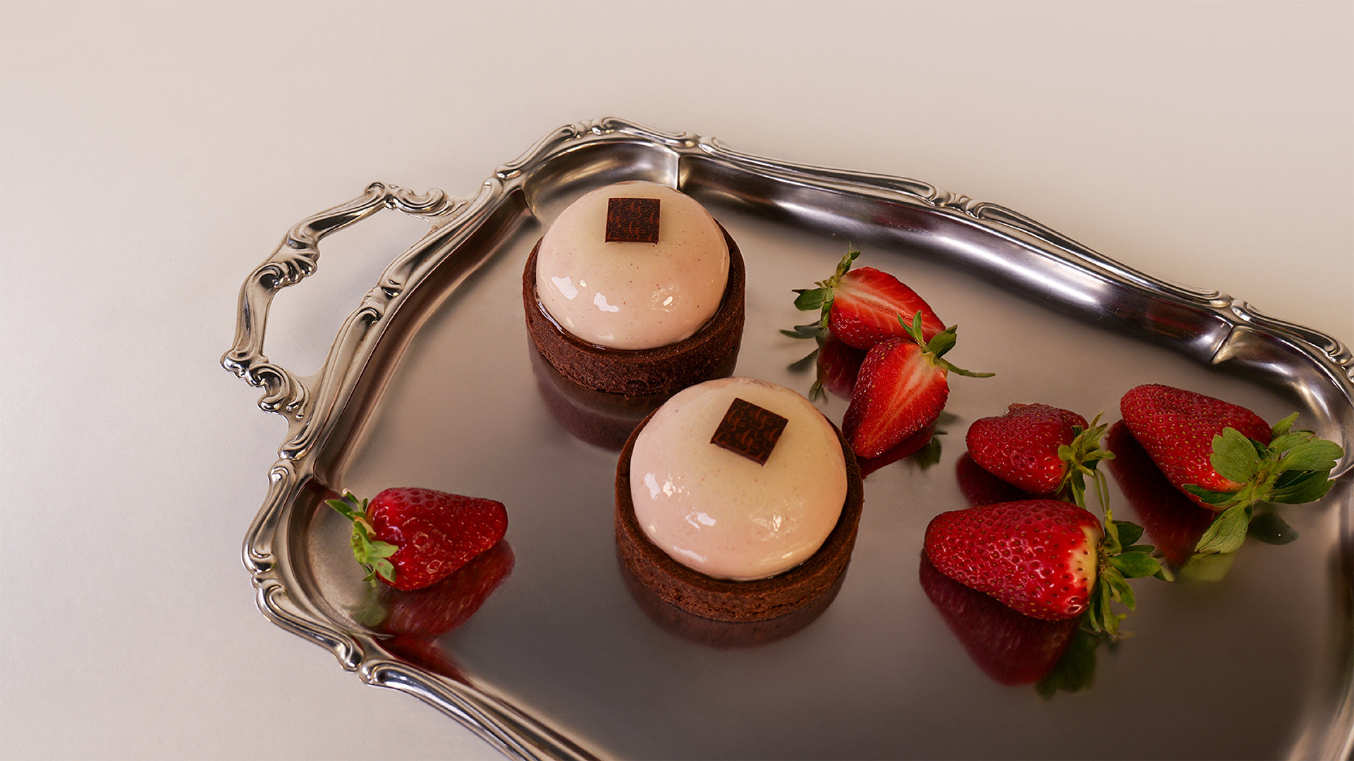 Dolci monoporzione al cioccolato con fragole, styling elegante su vassoio riflettente