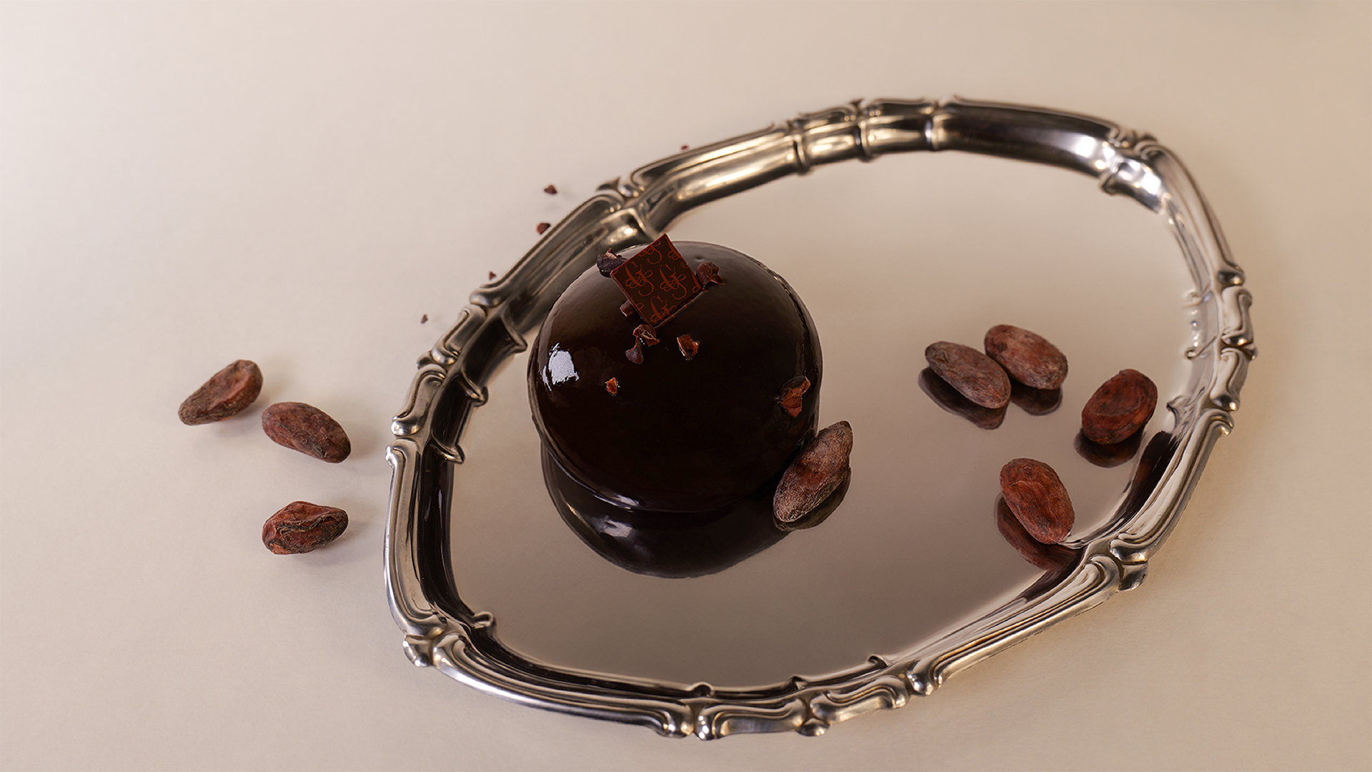Monoporzione al cioccolato su vassoio riflettente, styling food premium e atmosfera editoriale