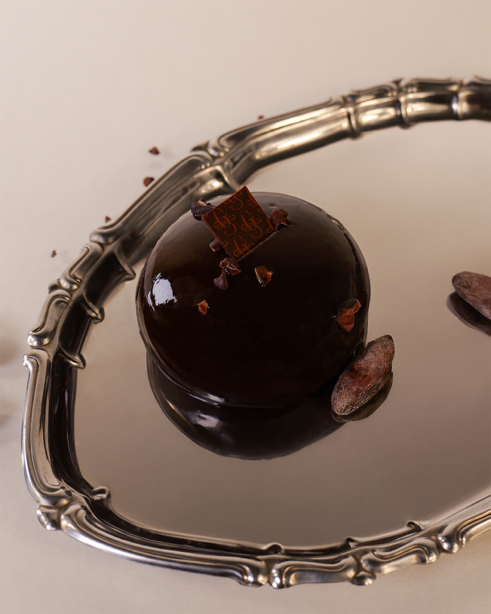 Monoporzione al cioccolato su vassoio riflettente, styling food premium e atmosfera editoriale dettaglio vista mobile