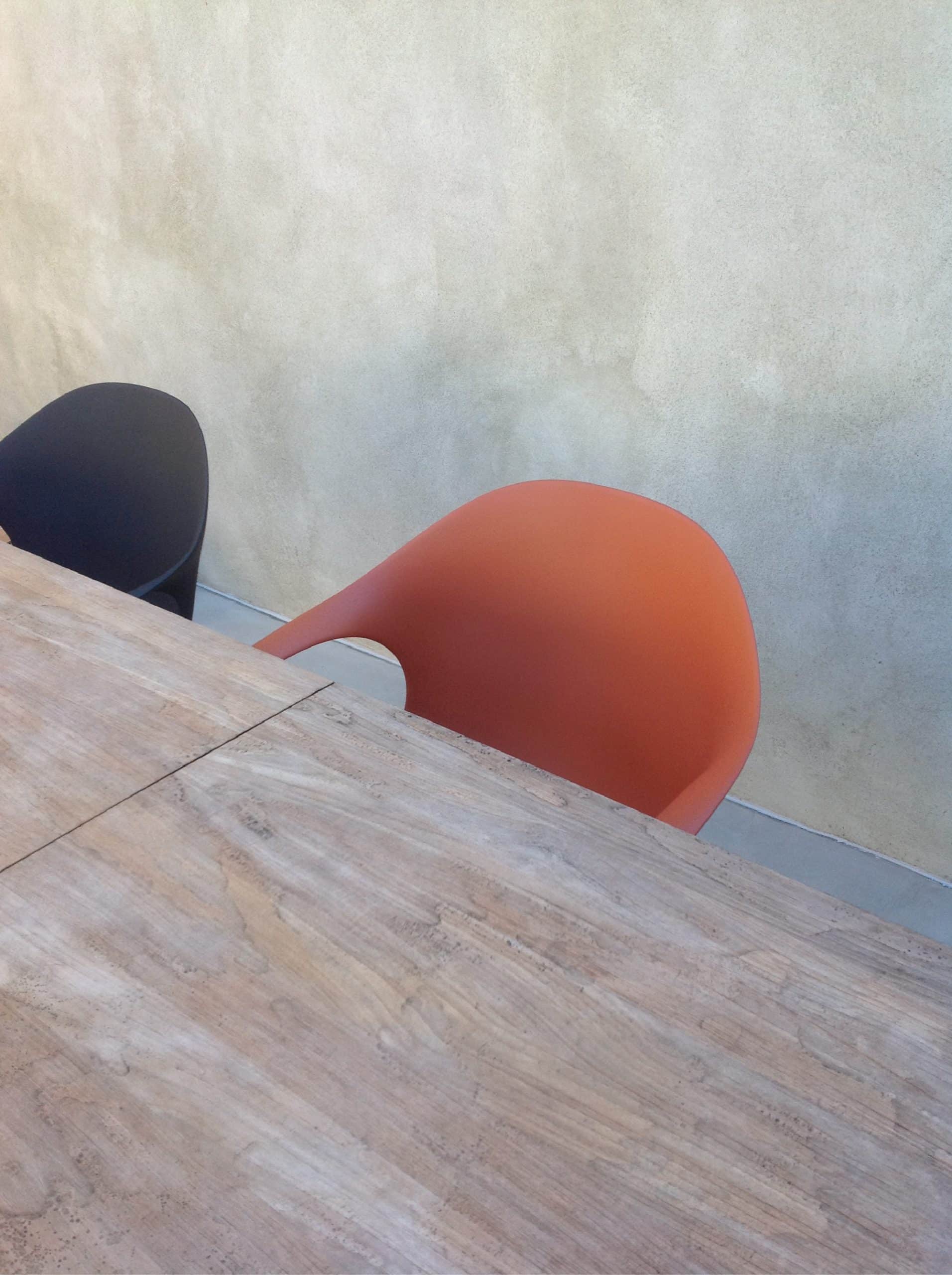 Tavolo in legno naturale con sedute di design color terracotta e blu in interno minimal - vista mobile