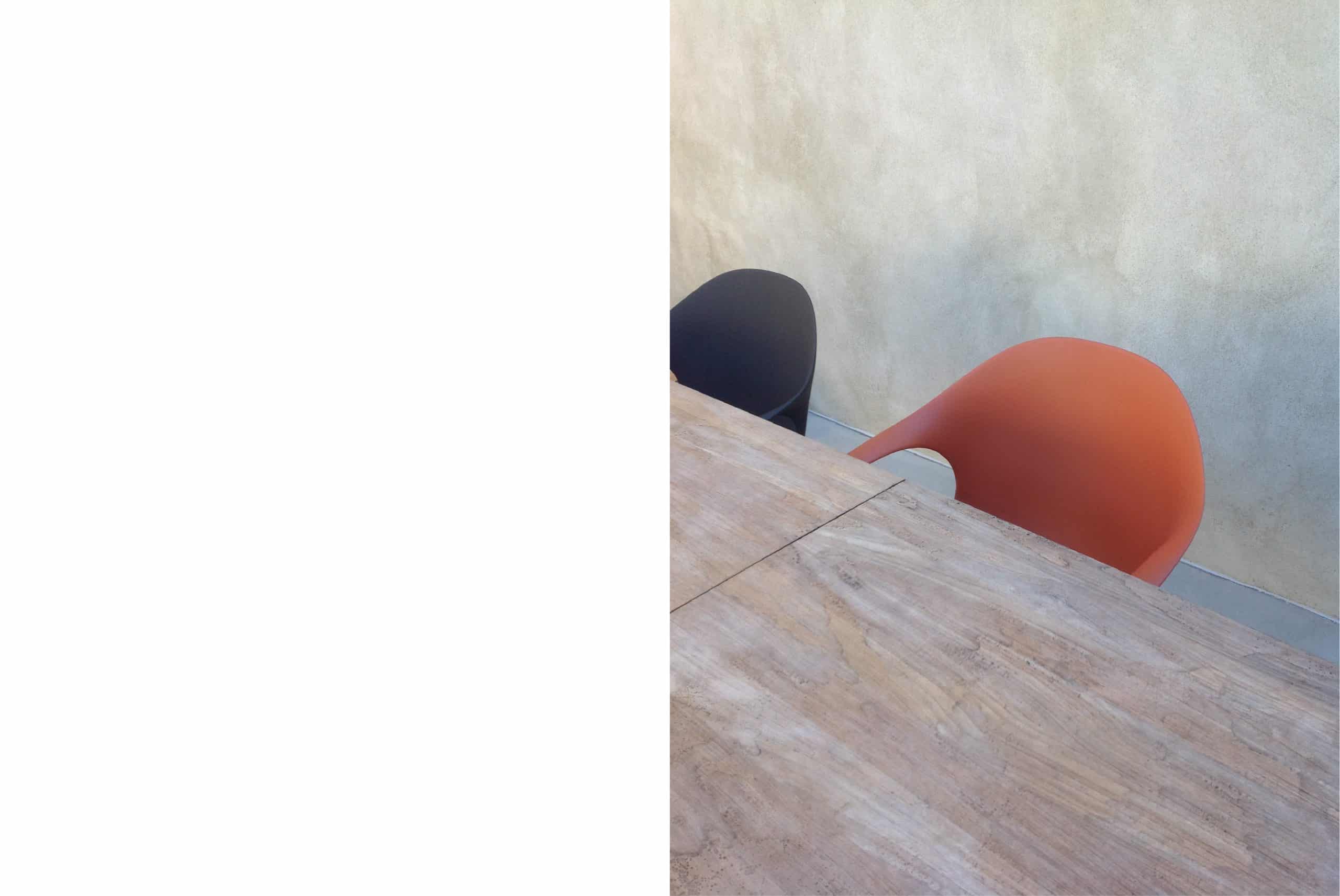 Tavolo in legno naturale con sedute di design color terracotta e blu in interno minimal