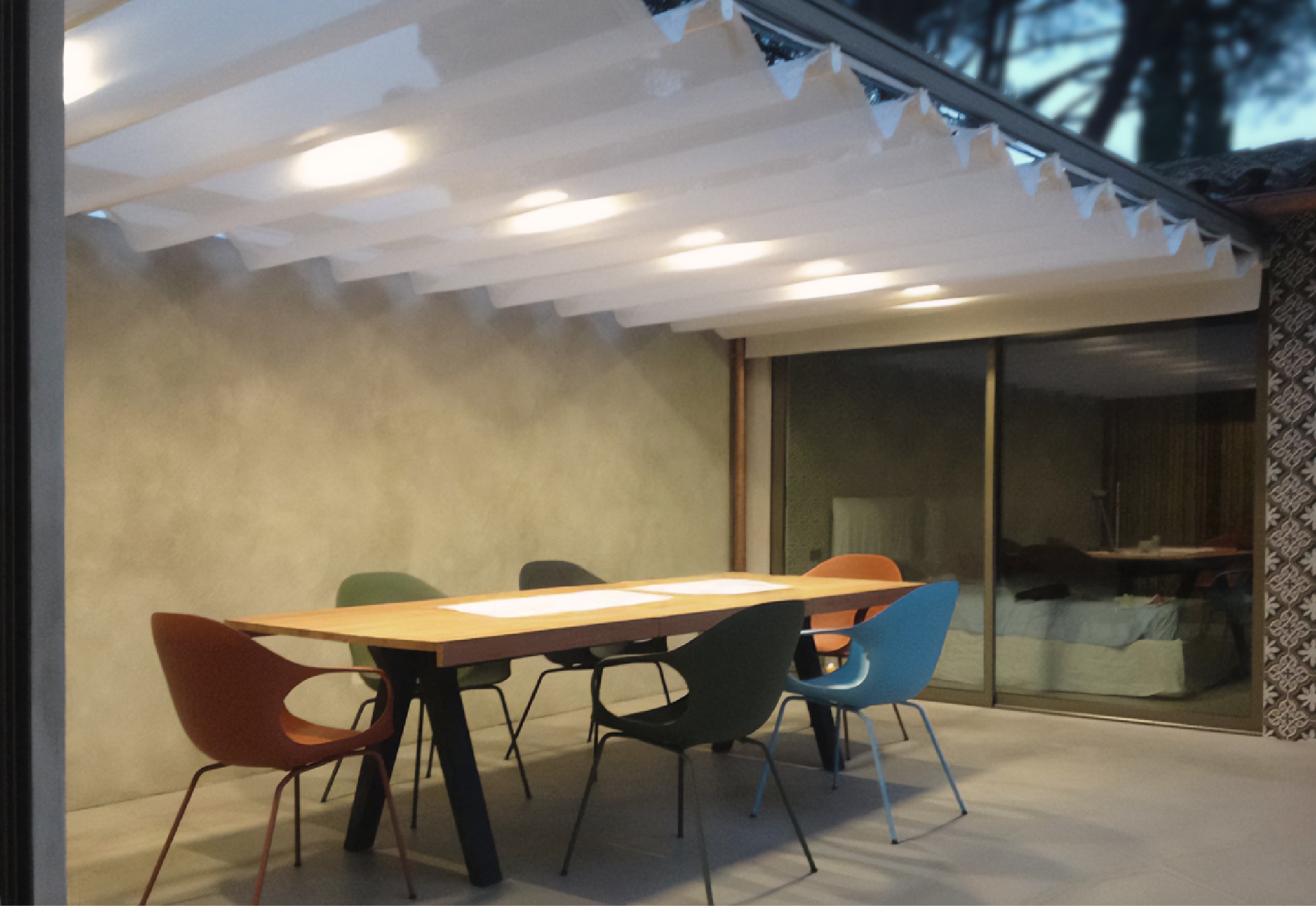 Terrazza coperta con tavolo in legno, sedute colorate e illuminazione integrata dal design contemporaneo - vista mobile