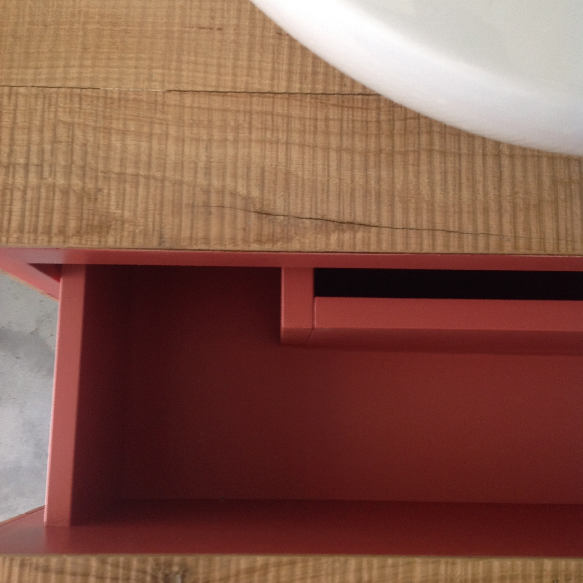 Dettaglio del mobile bagno in legno con inserto interno rosso e lavabo bianco appoggiato sul piano.
