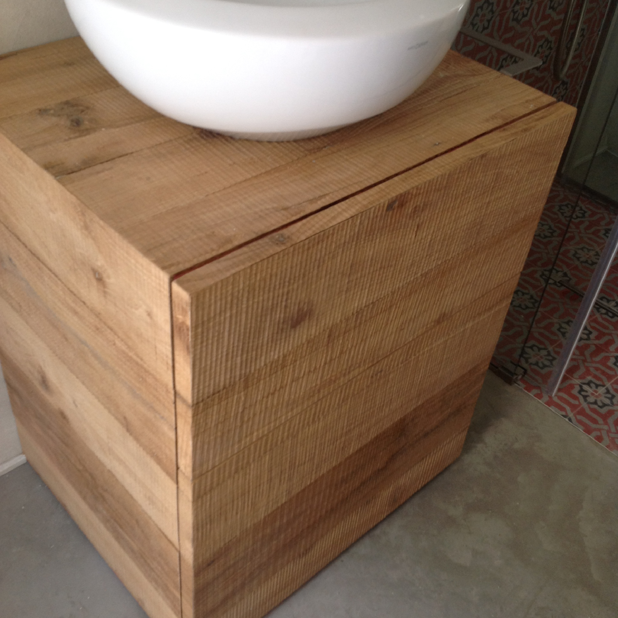 Mobile bagno in legno naturale con lavabo bianco, pavimento decorato e pareti grigie nel progetto del bastidon.