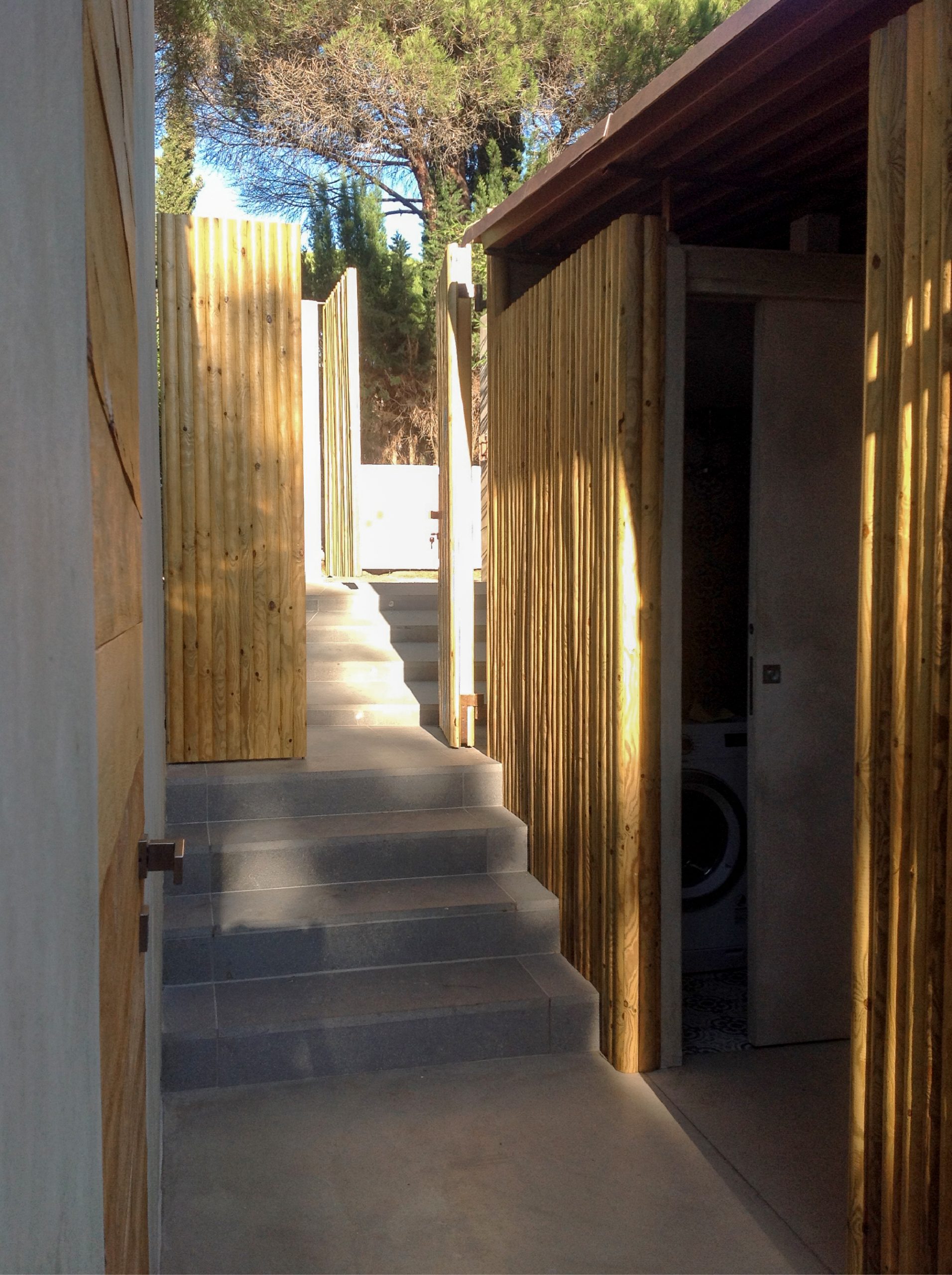 Passaggio esterno del bastidon con scala in pietra, pannelli in legno naturale e accessi integrati nel progetto architettonico.