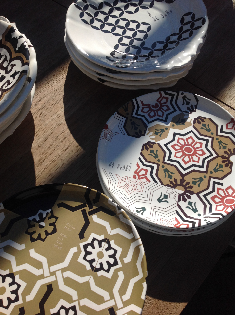Dettaglio di piatti decorativi su tavolo in legno, con pattern grafici ispirati ai rivestimenti del bastidon-mobile